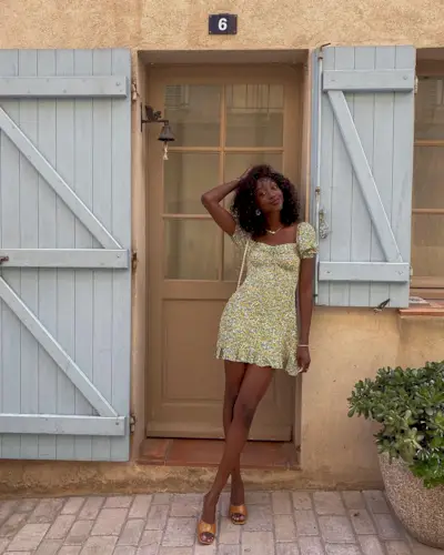 A woman wearing a floral minidress with tan sandals.
