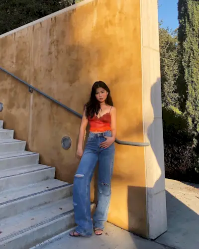 Allison Ho wearing a red camsiole with straight-leg jeans and black sandals.
