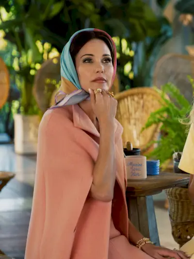 Leslie Bibb wears a peach cape and a colorful headscarf in Palm Royale season 2