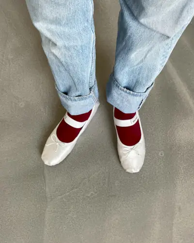 @annelauremais wears a pair of white Miu Miu satin ballet flats with burgundy socks and blye jeans