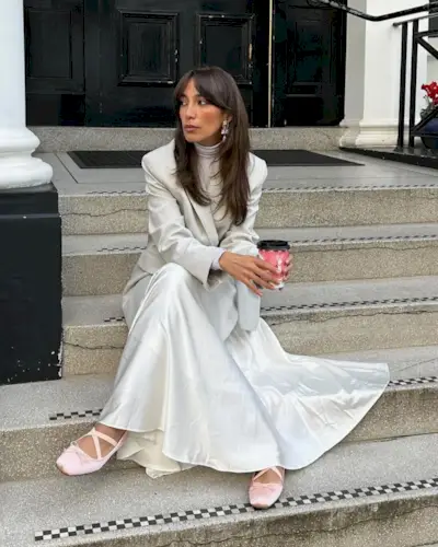 Influencer @iamsaraouardii wears a white satin skirt with a whit4e blazer and satin ballet flats.