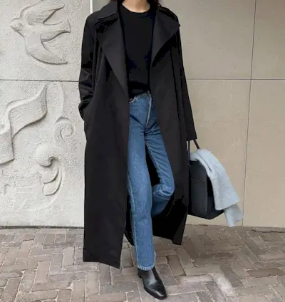 woman wearing slim jeans and black trench coat