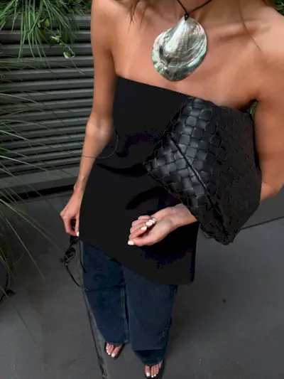 An image of @cocoschiffer wearing a black waisted top, one of the key summer tops trends of 2025.