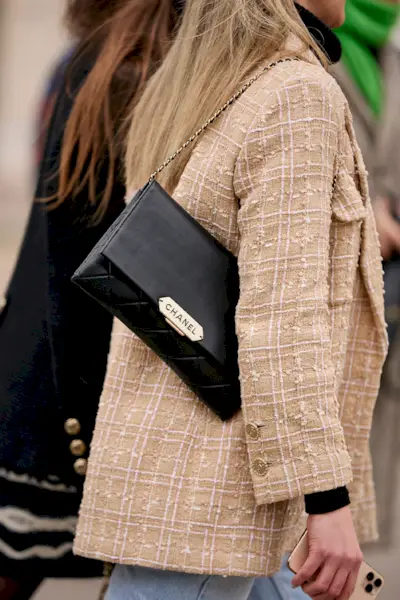 most popular chanel bags shown in a street style photo of a woman carrying a chanel wallet chain bag