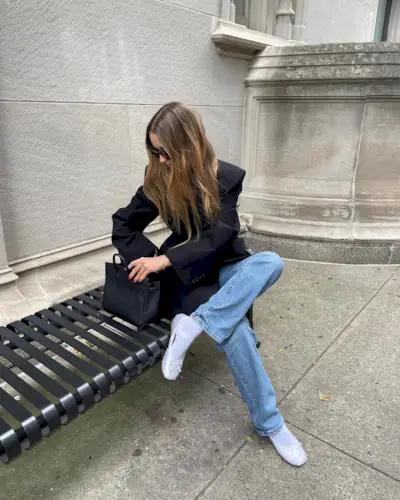 fitted blazer trend is shown on a woman wearing a black blazer with straight-leg denim and white ballet flats