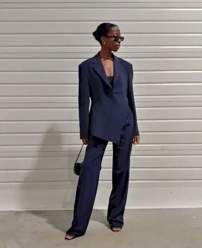 fitted blazer trend is shown on a woman wearing a navy blazer with navy trousers and black sandals