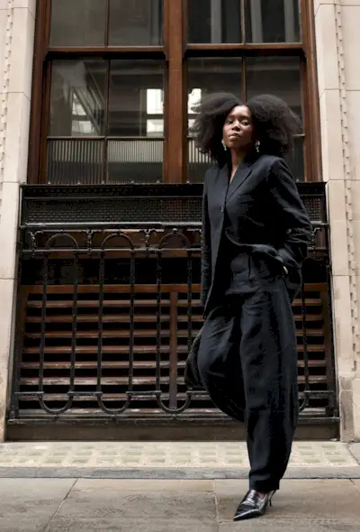 fitted blazer trend is shown on a woman wearing a black fitted blazer with matching trousers and slingback heels