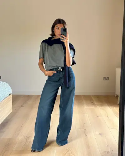 An image of @smythsisters wearing wide-leg trousers with a grey t-shirt and a navy sweater.