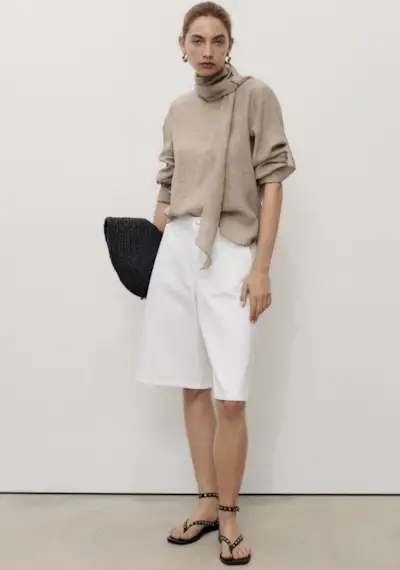 junior fashion editor Imani wears the Arket white denim Bermuda shorts with a white tank stripped shirt and black belt in the Arket changing rooms in a image taken recently.