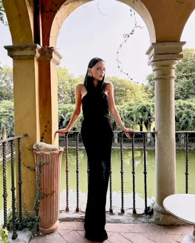 a photo showing cocktail attire for women with a woman wearing a black one piece jumpsuit