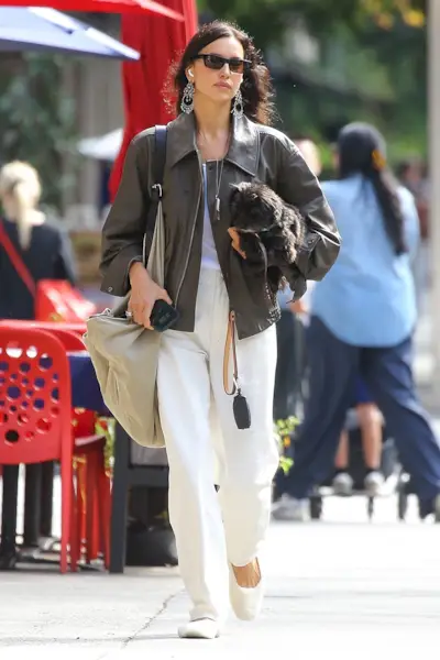 Irina Shayk wearing a brown leather bomber jacket, cream jeans, and cream fur ballet flats in NYC