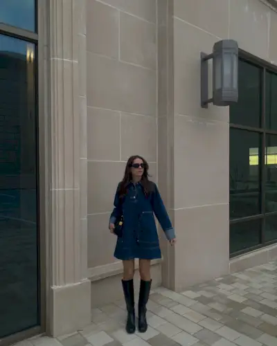 Brooke is wearing the denim dress trend. She pairs her Aligne denim dress, with knee high boots and sunnies. She is looking into the distance in a recent image from her Instagram.