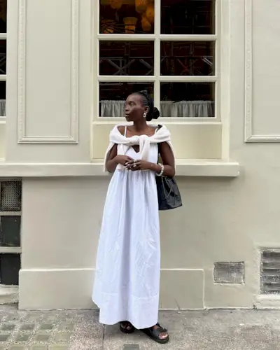 @daniellejinadu wearing a white dress with black sandals