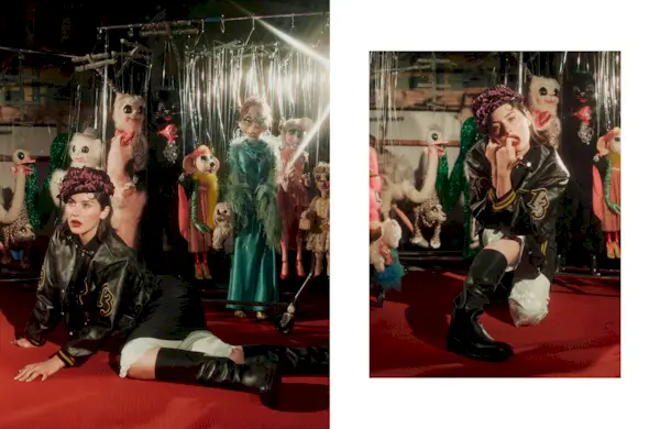 Two side-by-side photos of Gracie Abrams on the set of Mommy's Reviews's fall issue cover shoot wearing a F/W 24 Prada cap, leather letterman jacket, skirt, pants, and boots in front of a bunch of puppets at a marionette theatre.