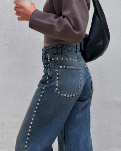 Influencer @tamaramory wears stud-embellished jeans with a brown cardigan and black bag.