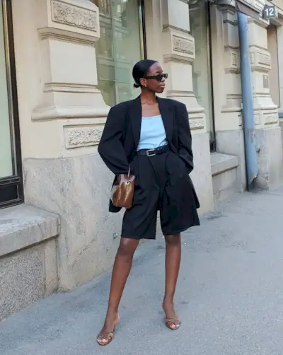 Woman wearing a black blazer and matching long shorts with heels.