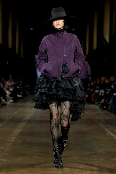 A McQueen model wearing a purple zip-up jacket and black tiered skirt