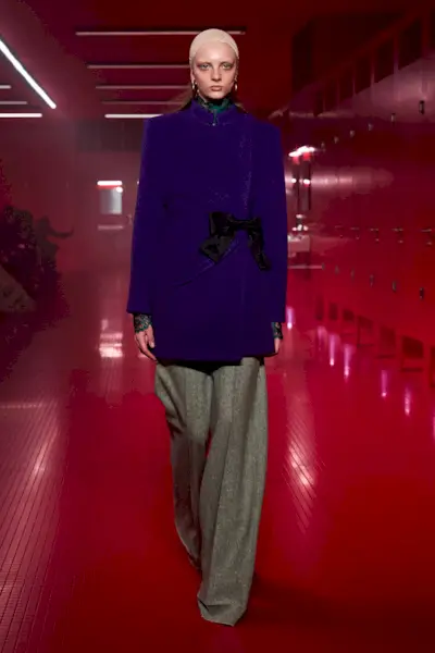 A Valentino model wearing a purple coat and gray pants