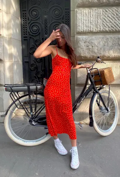 a photo of a woman wearing a red dress with white sneakers