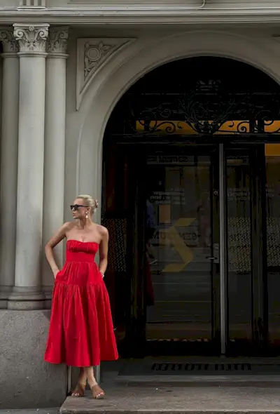 a photo of a woman wearing a strapless red dress and tan mules