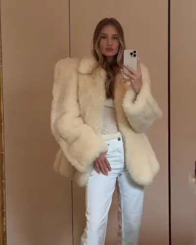 Rosie Huntington-Whiteley wearing a fur coat and white jeans.