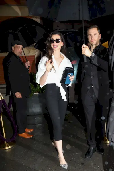 Anne Hathaway exits a star-studded Met Gala after-party in New York City, wearing her white cotton shirt from the blue carpet with pedal pushers and silver shoes.