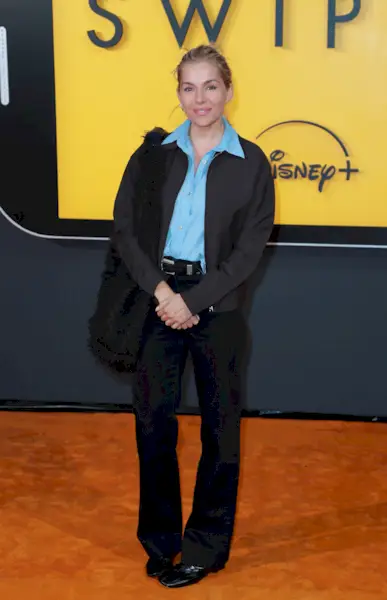 Sienna Miller steps out in London wearing black jeans with square-toe flats, a blue shirt and a dark brown jacket.