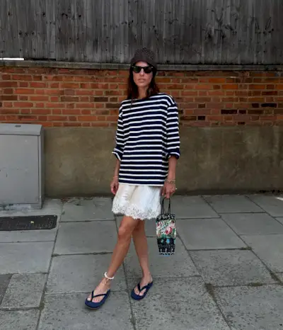 @lauravidrequin wearing a striped navy T-shirt with a cream lace-trim skirt and flip-flops.