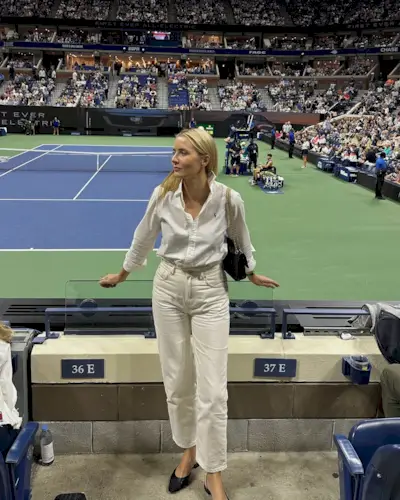 Woman wearing a white shirt and white jeans to a tennis match.