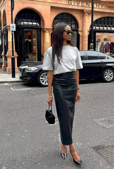 a black maxi skirt outfit showcasing a woman wearing a black sunglasses with a gray t-shirt tucked into a black leather maxi skirt with patent black slingback heels and a black handbag