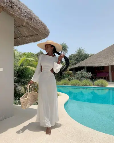 a photo of a woman's beach outfit with a raffia hat and cutout knit dress with woven tote bag