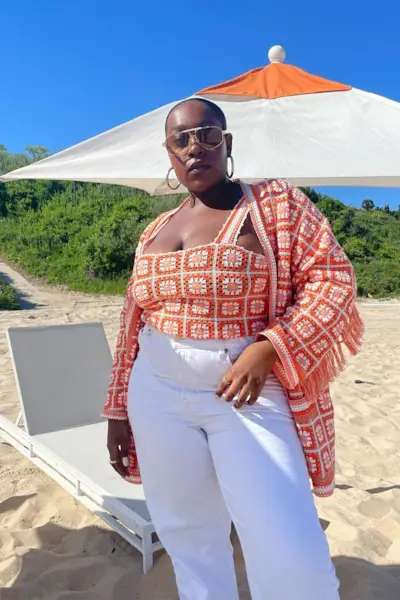 a photo of a woman's beach outfit with aviator sunglasses and hoop earrings and crochet set and white jeans