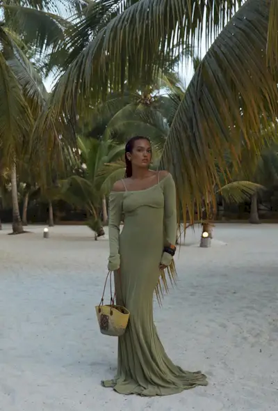 a photo of a woman's beach outfit with a green maxi dress and layered bangles and raffia bag