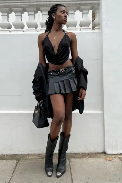 a photo of a club outfit with a woman wearing a black halter top with a black leather miniskirt and black cowboy Boots