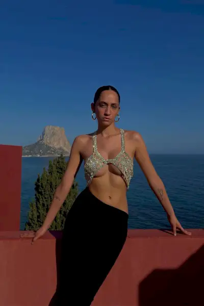 a photo of a club outfit with a woman wearing a sparkly bra top with a low-rise skirt and hoops