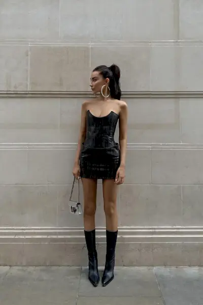 a photo of a club outfit with a woman wearing corset and matching miniskirt and knee-high boots and shoulder bag