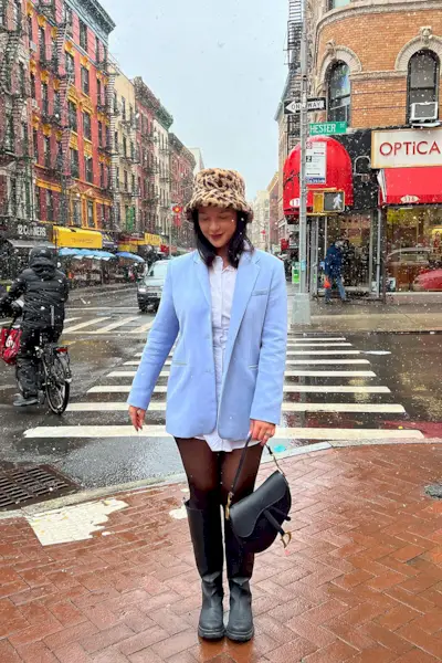 outfits to wear on a first date shown on a woman wearing a blue blazer over a white shirt dress with black tights and black knee high boots