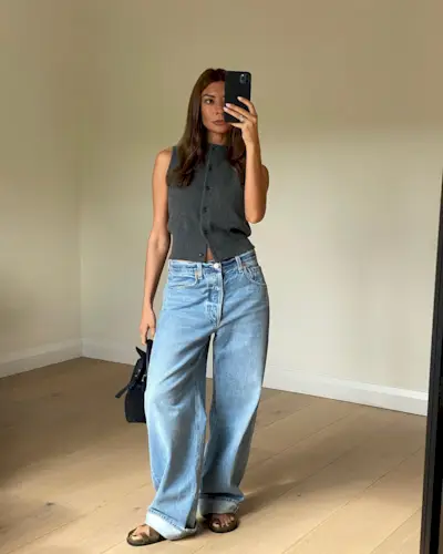 Woman wearing a stylish outfit with cuffed jeans.