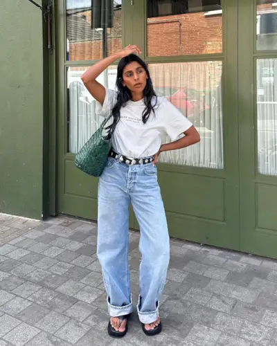 Woman wearing a stylish outfit with cuffed jeans.