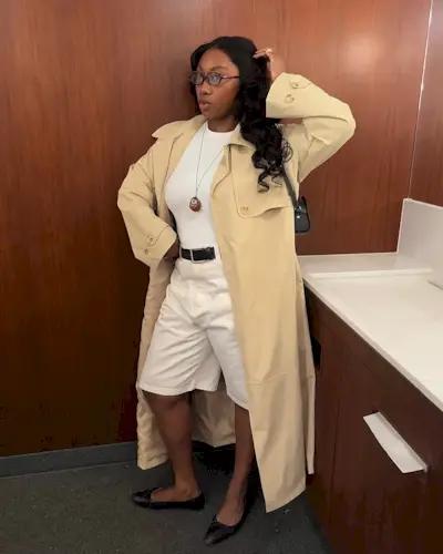 woman wearing long white shorts and long trench coat with ballet flats