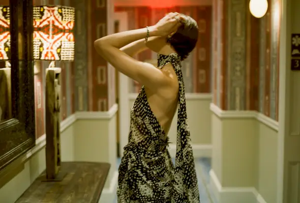 Actress Louisa Jacobson wears a scarf-print Dries Van Noten halter dress with Sauer jewels. She is posing for portraits inside her hotel room before The Gilded Age season 3 premiere.