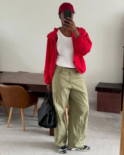 Influencer @nlmarilyn takes a mirror selfie wearing a red jacket, khaki trousers and a red cap.