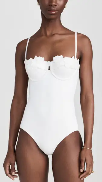 a model wears a white one-piece swimsuit with a floral embroidered design at the bust