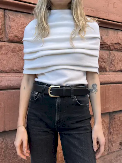 Cream top with black jeans and a black belt with gold hardware