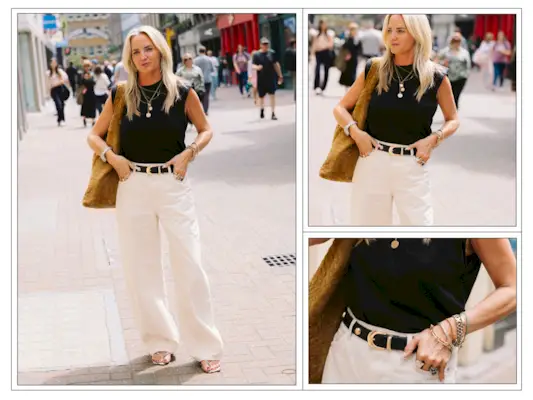 A woman wears cream jeans and a black top with a studded belt in London