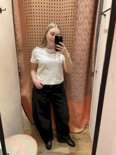 Woman wears white t-shirt and black barrel-leg jeans
