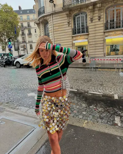A woman wearing a striped long sleeve shirt and a sequin skirt