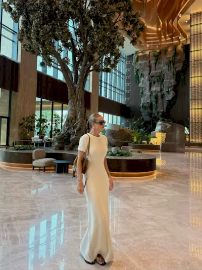 Rosie Huntington-Whiteley wears a longline boucle t-shirt dress with a light khaki suede handbag, flip-flops and dark sunglasses.