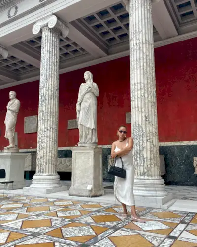 Jasmine Fox-Suliaman wearing a white slip dress, mesh ballet flats, and a black shoulder bag at an art museum in Copenhagen.