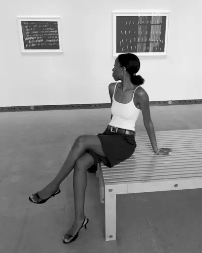 Fashion influencer Sylvie Mus wearing a tank top, tailored shorts, and slingbacks at an art museum.
